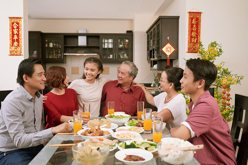 Happy family sitting at dinner table and celebrating Lunar New Year